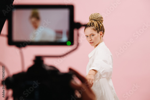 Woman with blond afro braids posing in front of a camera with field monitor