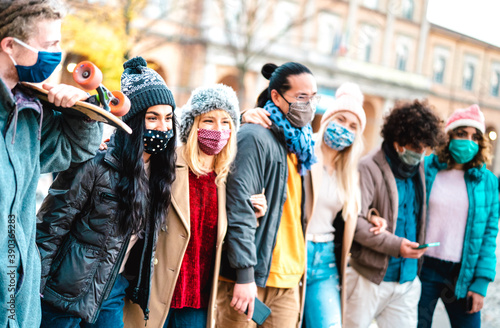 Millennial people group walking and having fun together wearing face mask at city center - New normal friendship concept with multicultural friends on winter fashion clothes - Bright vivid filter