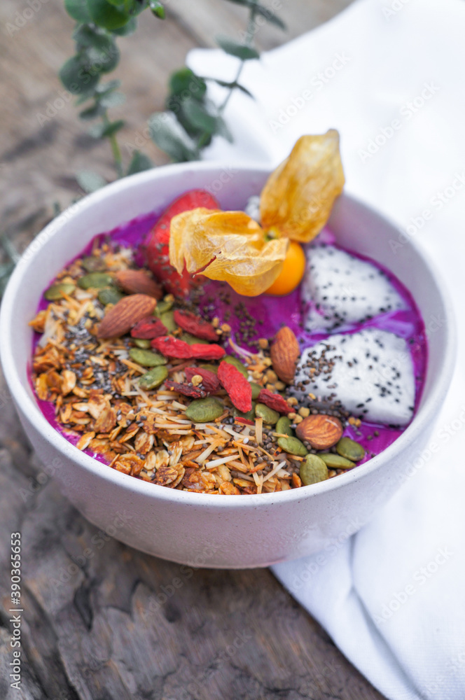 Fototapeta premium Selective focus Purple smoothie bowl: Dragon fruit smoothie with banana, coconut, almonds, sunflower and chia seeds and strawberry