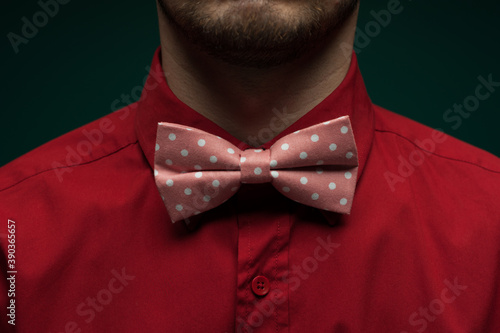 Close-up of a young man in a red shirt and bow-tie against a green background Fototapete