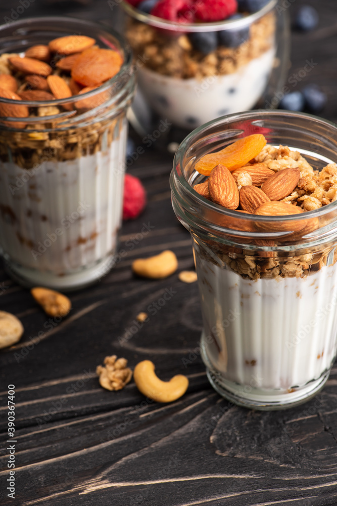 delicious granola with dried apricots, nuts and yogurt in glass cup on blurred background delicious granola with dried apricots, nuts and yogurt in glass cup on blurred background