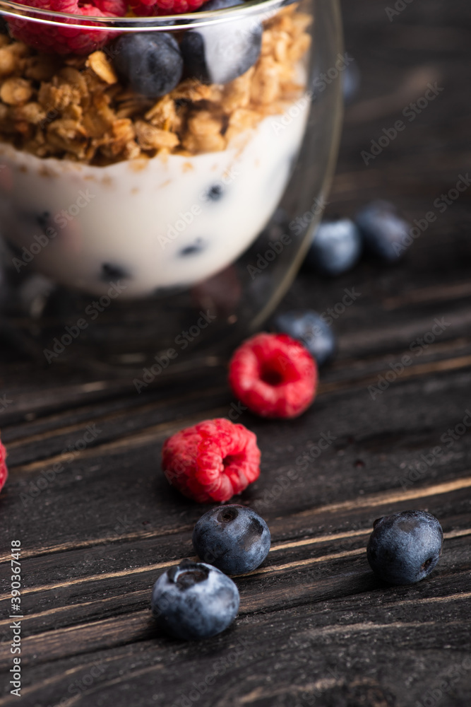 closeup of delicious granola with berries and yogurt in glass cup on wooden surface closeup of delicious granola with berries and yogurt in glass cup on wooden surface