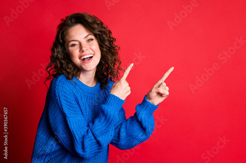 Photo of cute lovely lady curly hairstyle raise hands indicate fingers up empty space open mouth laughing cheerful smile wear blue knitted pullover isolated red color background