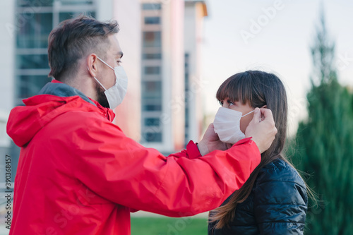 A man puts on a medical mask for a girl. against the background of the city.