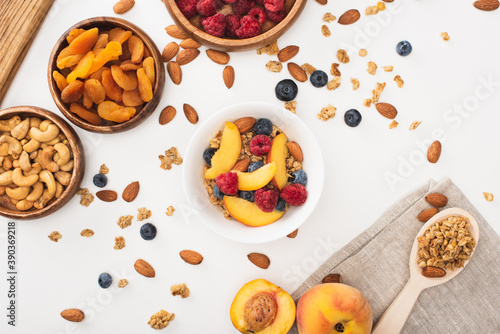 top view of delicious granola with nuts, raspberry, peach, blueberry and dried apricots isolated on white