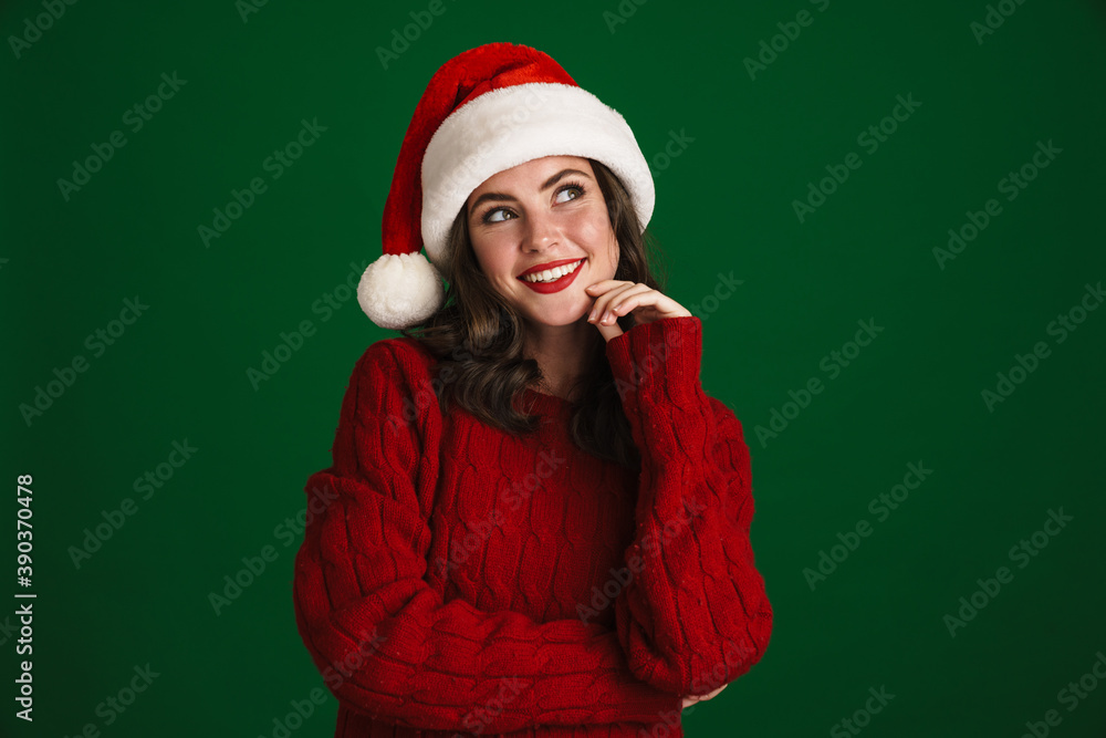 Beautiful joyful girl in Santa Claus hat smiling and looking upward Beautiful joyful girl in Santa Claus hat smiling and looking upward
