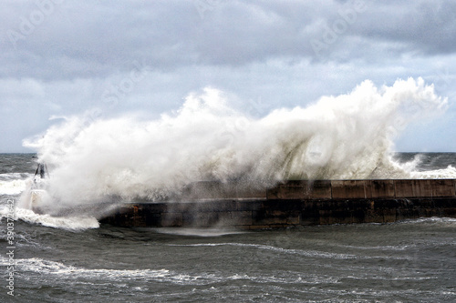 Stormy sea waves breaking over a harbour wall
