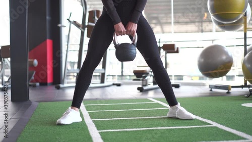 Front of woman in sportswear exercise with kettlebell at gym
