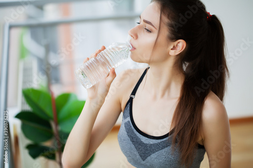 Tablou canvas Woman drinking water at the gym after working out