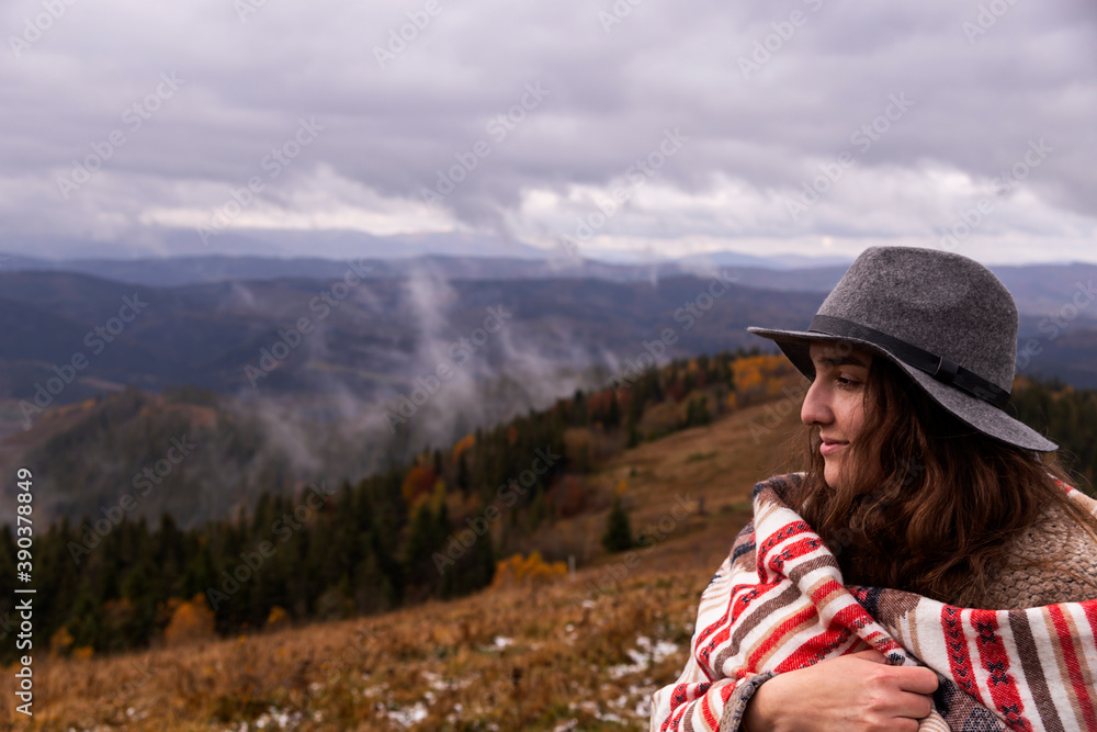 Girl traveler in the mountains in boho clothes with a hat. Enjoys nature and travel. Local camping concept. Copy space