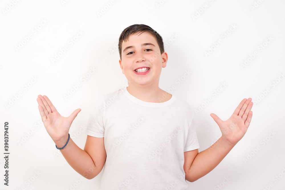 Caucasian young boy standing against white background raising hands up, having eyes full of happiness rejoicing his great achievements. Achievement, success concept. Caucasian young boy standing against white background raising hands up, having eyes full of happiness rejoicing his great achievements. Achievement, success concept.