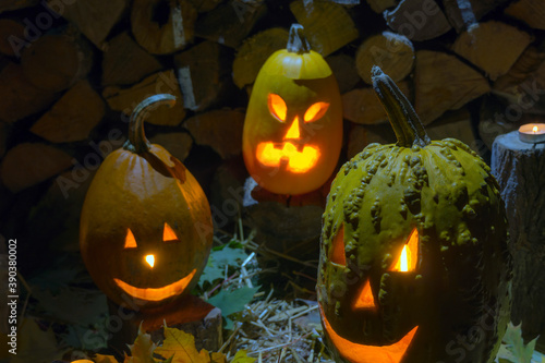 Three glowing pumpkins on the background of firewood at night on Helovin. photo