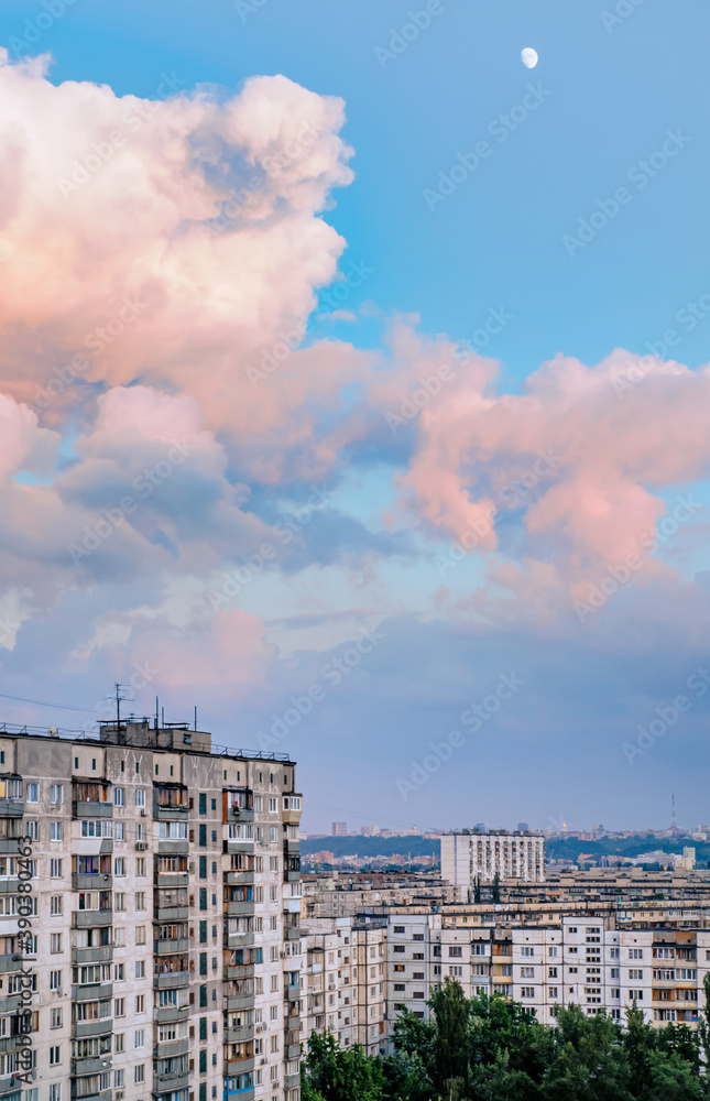 High buildings in the Obolon district of Kiev, Ukraine, near the Minska metro station. Big pink clouds in the sky, and the Moon