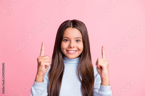 Close-up portrait of pretty cheerful brown-haired teen girl pointing forefingers up copy space isolated over pink pastel color background