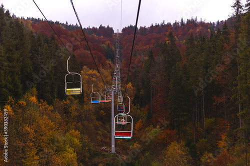 Ski lift in autumn mountains among beautiful views with yellow and red trees. Wanderlust concept
