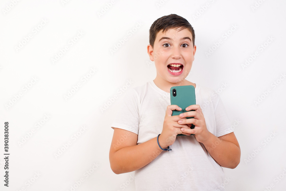 Smiling Caucasian young boy standing against white background friendly and happily holding mobile phone taking selfie in mirror. Smiling Caucasian young boy standing against white background friendly and happily holding mobile phone taking selfie in mirror.