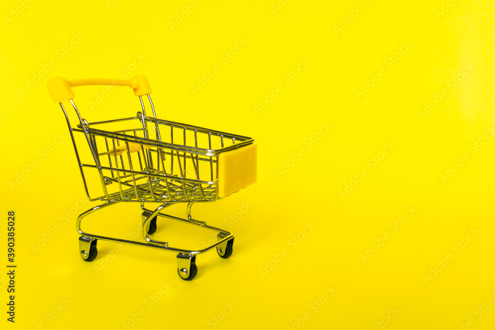 Empty shopping grocery cart on yellow background. Concept of business, shopping, black friday sales.