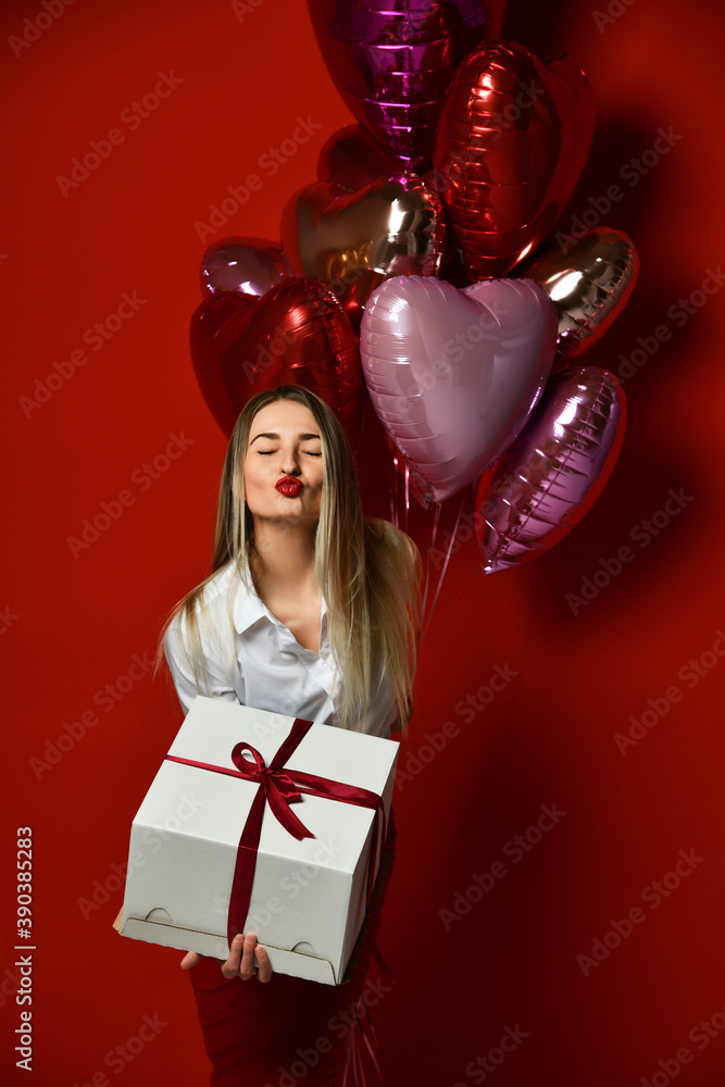 Blonde woman with present big gift box and purple pink heart balloons for new year 2021 sends a kiss Blonde woman with present big gift box and purple pink heart balloons for new year 2021 sends a kiss