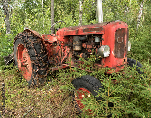Old red tractor in autumnal forest. A rusty old disused tractor in woodland. 