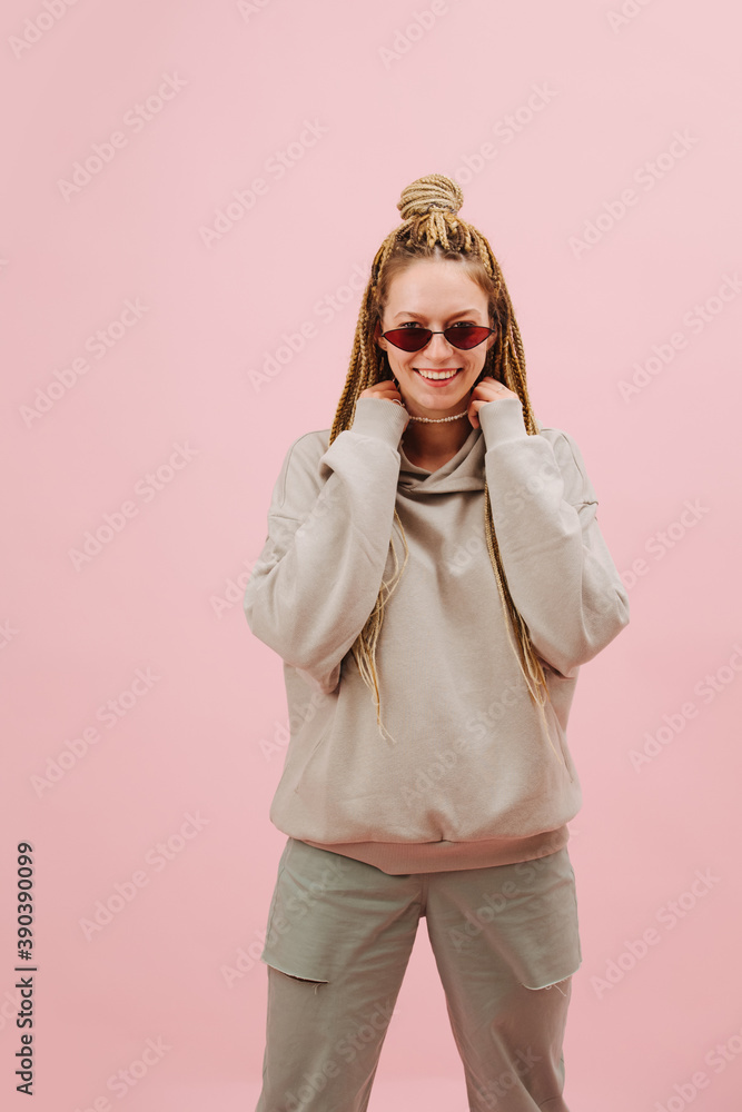 Entertained woman in sunglasses with stylish blond afro braids over pink Entertained woman in sunglasses with stylish blond afro braids over pink