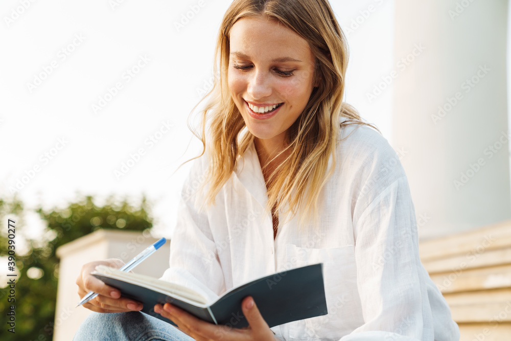 Beautiful happy student girl writing down notes in exercise book Beautiful happy student girl writing down notes in exercise book