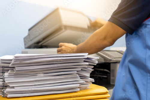 The papers stacked waiting to be copied with a copier machine. photo