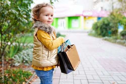 Beautiful little girl shopping holding colorful paper bags outdoors