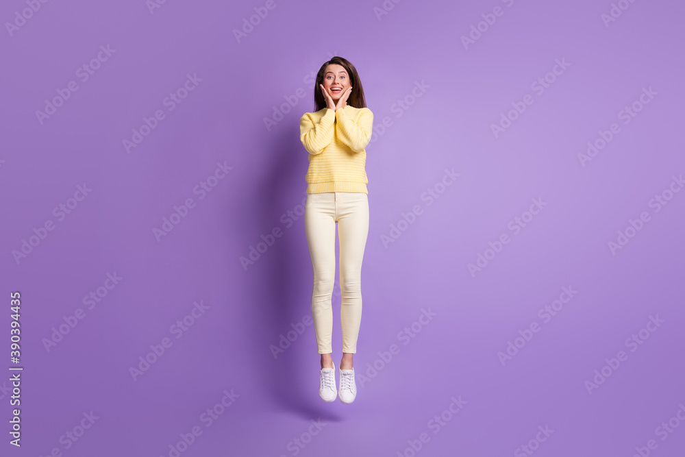 Full length photo portrait of adorable girl jumping up touching face cheeks with two hands isolated on bright purple colored background