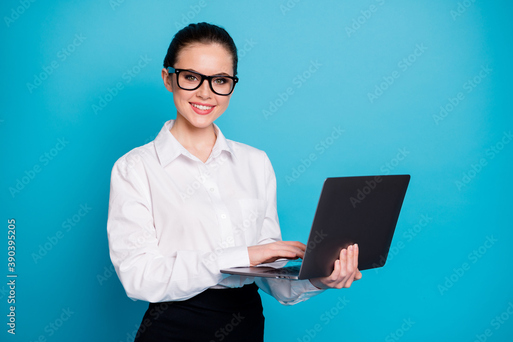 Portrait of attractive cheerful geek specialist girl holding in hands laptop browsing isolated over bright blue color background Portrait of attractive cheerful geek specialist girl holding in hands laptop browsing isolated over bright blue color background