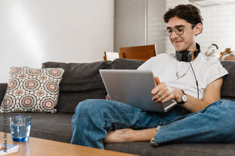 Handsome man indoors at home using laptop computer Handsome man indoors at home using laptop computer