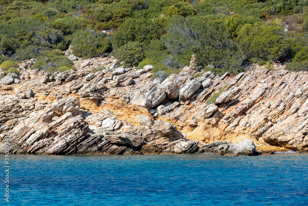 Grass, rocks and turquoise water at the Aegean sea