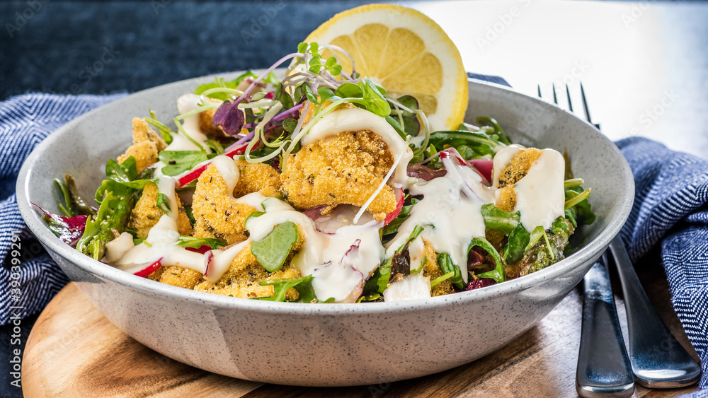 A plate of crispy Calamari Salad with lettuce, radish, lemon, tomatoes, asparagus and avocado. A plate of crispy Calamari Salad with lettuce, radish, lemon, tomatoes, asparagus and avocado.