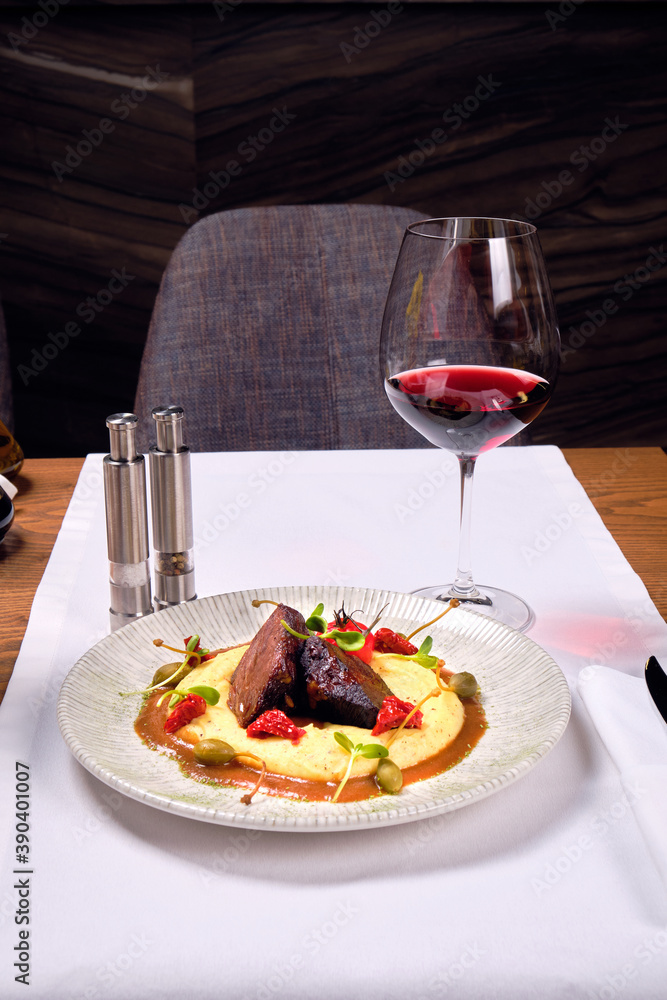Meat dish with mashed potatoes and a glass of red wine