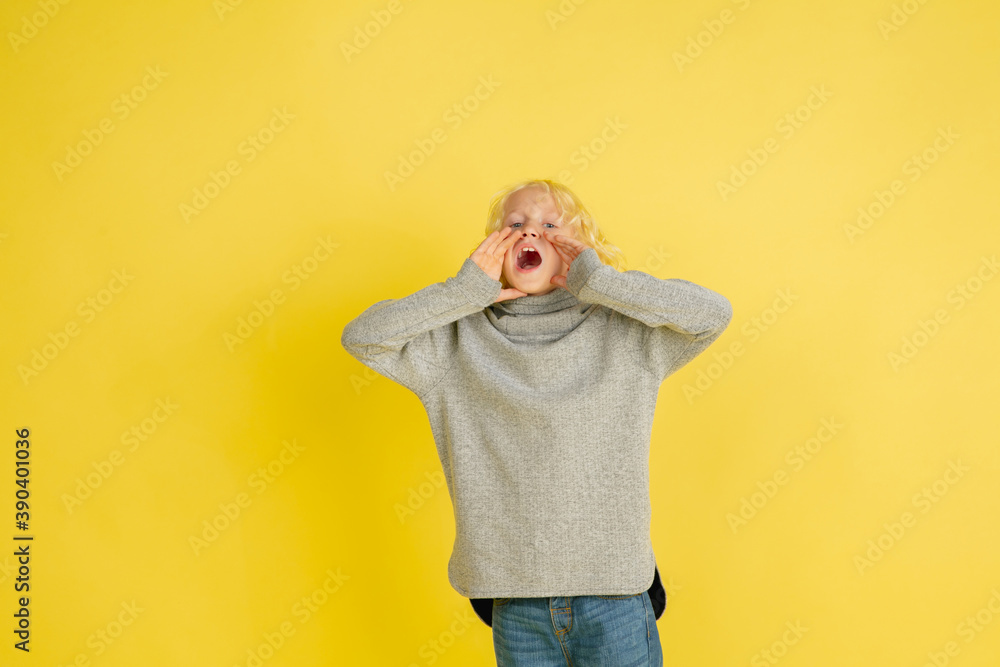 Shouting for sale, screaming. Portrait of little caucasian boy isolated on yellow studio background with copyspace. Beautiful model. Concept of human emotions, facial expression, sales, ad, youth. Shouting for sale, screaming. Portrait of little caucasian boy isolated on yellow studio background with copyspace. Beautiful model. Concept of human emotions, facial expression, sales, ad, youth.