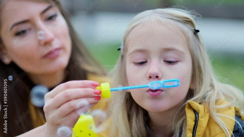 Happy family in park. Cute female child blows soup foam and make bubbles with her mother in nature. autumn park, spend time together. Family time. close up Shot video. Slow motion footage Happy family in park. Cute female child blows soup foam and make bubbles with her mother in nature. autumn park, spend time together. Family time. close up Shot video. Slow motion footage