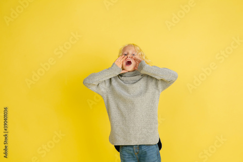 Shouting for sale, screaming. Portrait of little caucasian boy isolated on yellow studio background with copyspace. Beautiful model. Concept of human emotions, facial expression, sales, ad, youth. © master1305