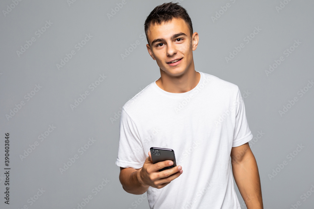Happy young man in glasses typing sms on gray background Happy young man in glasses typing sms on gray background
