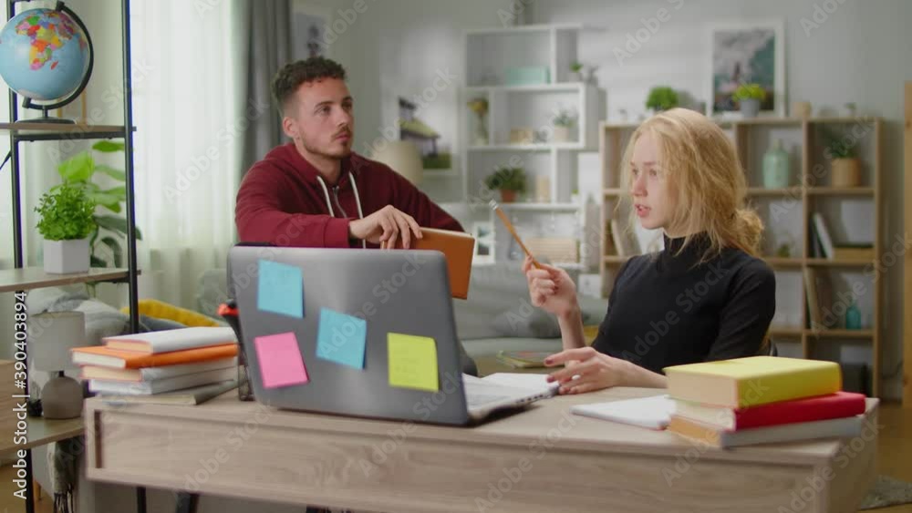 Young tutor man is studying with a young woman at her home during quarantine Young tutor man is studying with a young woman at her home during quarantine