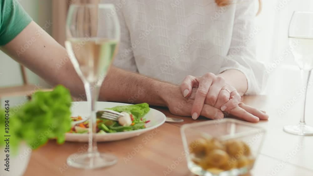 Medium shot of unrecognizable aged man and his beloved woman sitting together at dining table and holding hands of each other Medium shot of unrecognizable aged man and his beloved woman sitting together at dining table and holding hands of each other