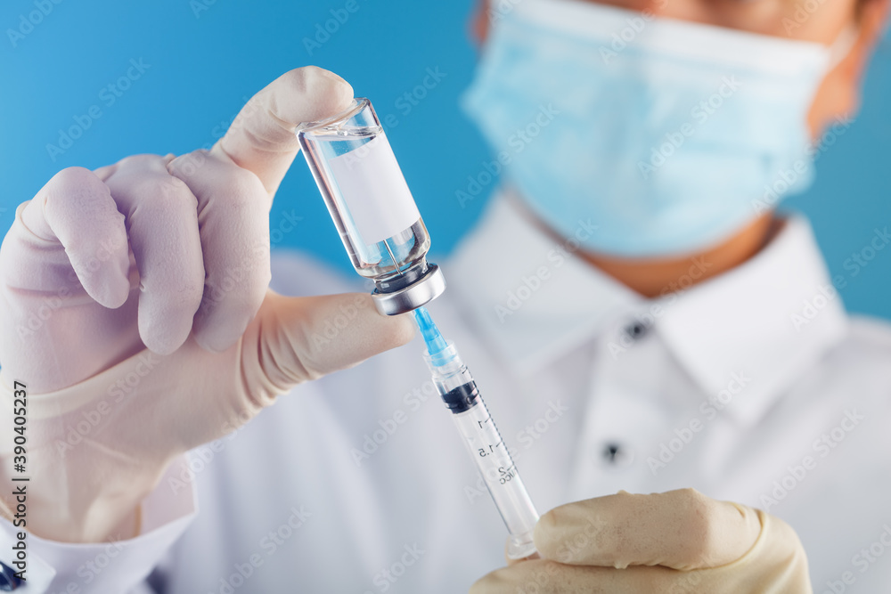 A doctor in rubber gloves holds an ampoule with a vaccine and a syringe, close-up. A doctor in rubber gloves holds an ampoule with a vaccine and a syringe, close-up.