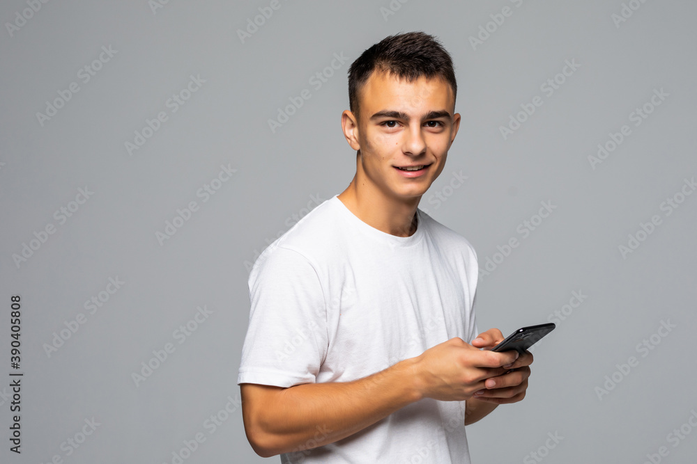 Portrait of young man typing on the phone isolated on gray background Portrait of young man typing on the phone isolated on gray background