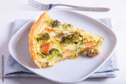 Quiche (open pie) with trout, broccoli and cheese. Homemade unsweetened pastries, traditional pie. Close-up.