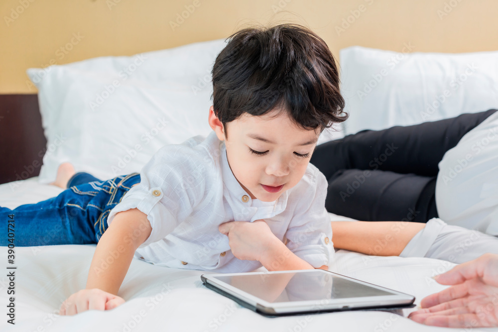 Cute asian boy thinking in front of tablet. Distance learning online education. Cute asian boy doing homework on bed at home. Cute asian boy thinking in front of tablet. Distance learning online education. Cute asian boy doing homework on bed at home.