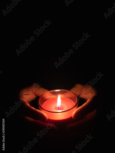 Red candle in male hands on a black background
