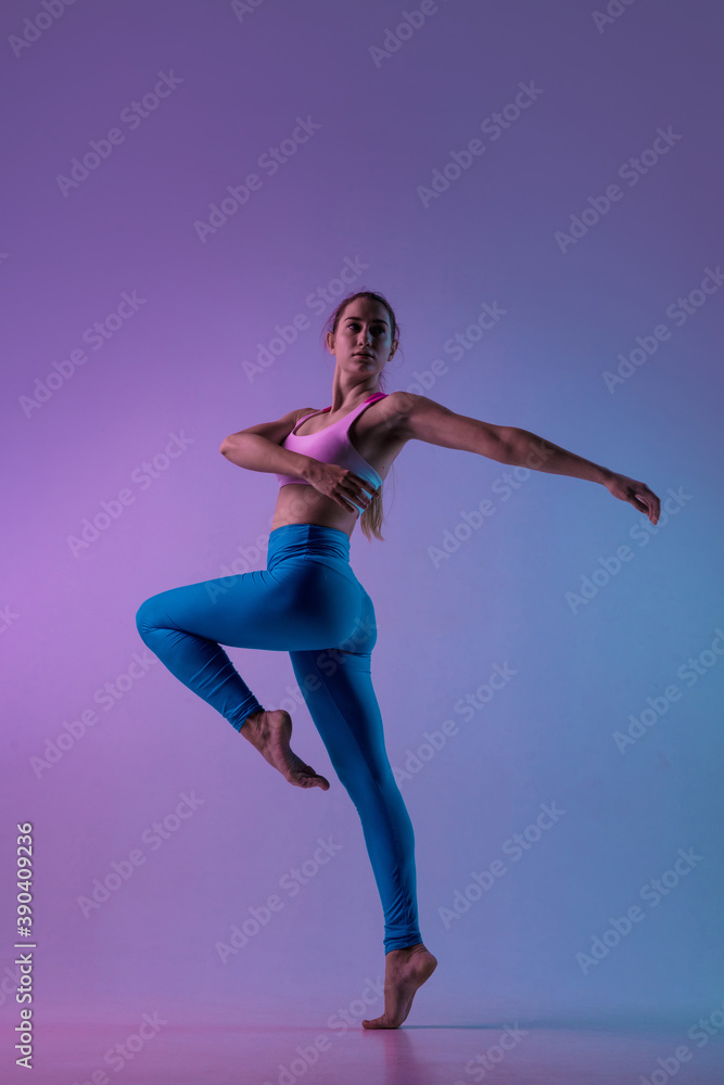 Graceful. Young sportive woman training isolated on gradient studio background in neon light. athletic and graceful. Modern sport, action, motion, youth concept. Beautiful caucasian woman practicing.