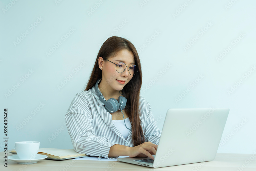 portrait of a beautiful Asian woman wearing glasses wears headphones Smile happily And look at the laptop While chatting online With colleagues On her desk At the home office, the idea of working at portrait of a beautiful Asian woman wearing glasses wears headphones Smile happily And look at the laptop While chatting online With colleagues On her desk At the home office, the idea of working at