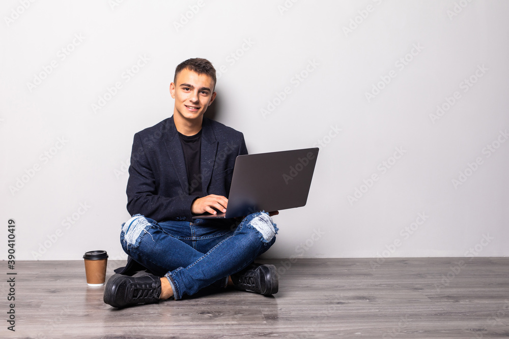 Young man working on laptop sitting on floor reading news, surfing net or freelancing isolated on white background Young man working on laptop sitting on floor reading news, surfing net or freelancing isolated on white background