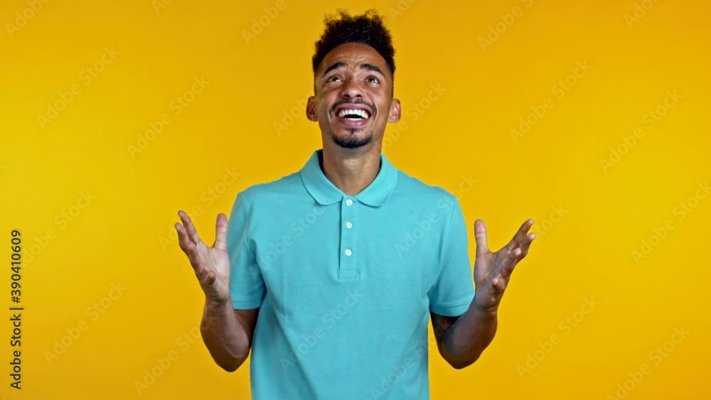 Young african stressed man shouting isolated on yellow background. Angry and depressed guy loudly screaming to camera. Young african stressed man shouting isolated on yellow background. Angry and depressed guy loudly screaming to camera.