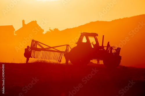 Tractor in a farm field at sunset. Backlight warm tones.