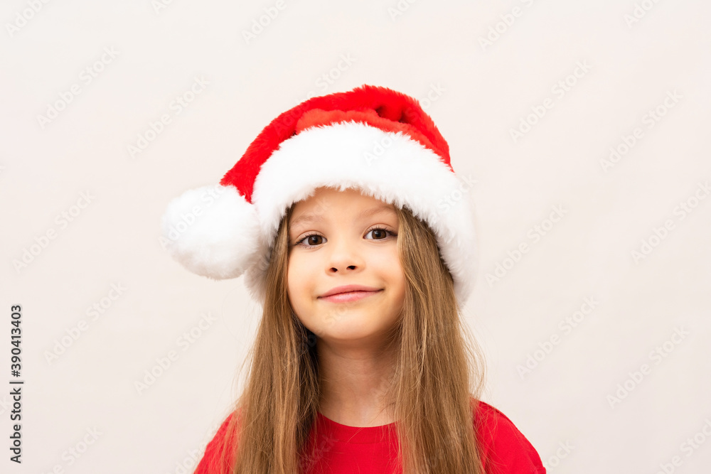 A beautiful little girl in a red t-shirt and a Christmas hat. A beautiful little girl in a red t-shirt and a Christmas hat.